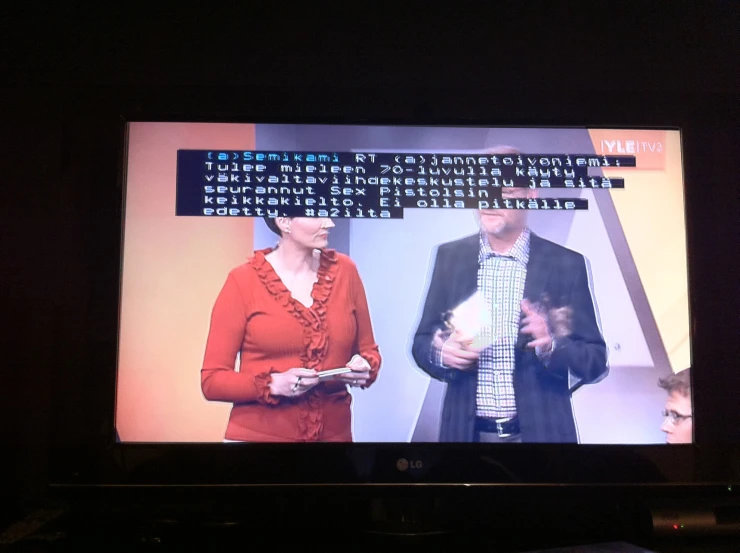 a television screen showing a news program with two people on the tv