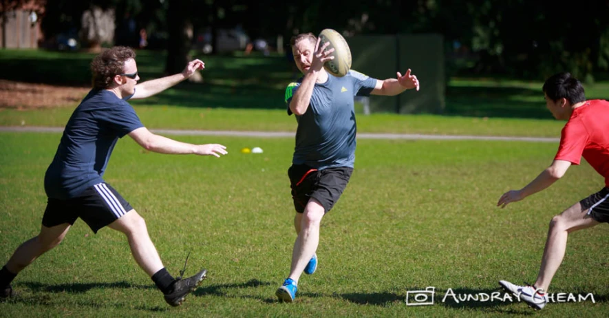 four men play with a disc in the park