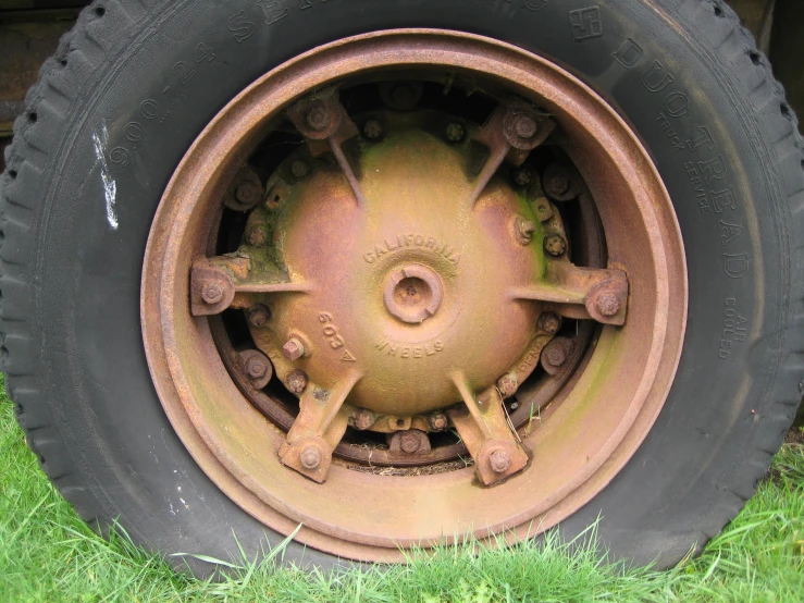 a worn tire sits in the grass beside a truck tire