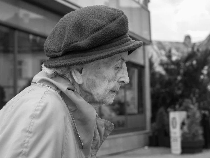 old man with hat and scarf standing in front of store