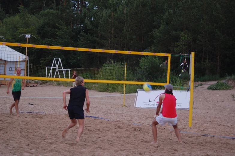 people playing beach volleyball in the sand on a sunny day