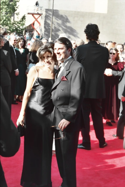 two people standing on a red carpet next to each other