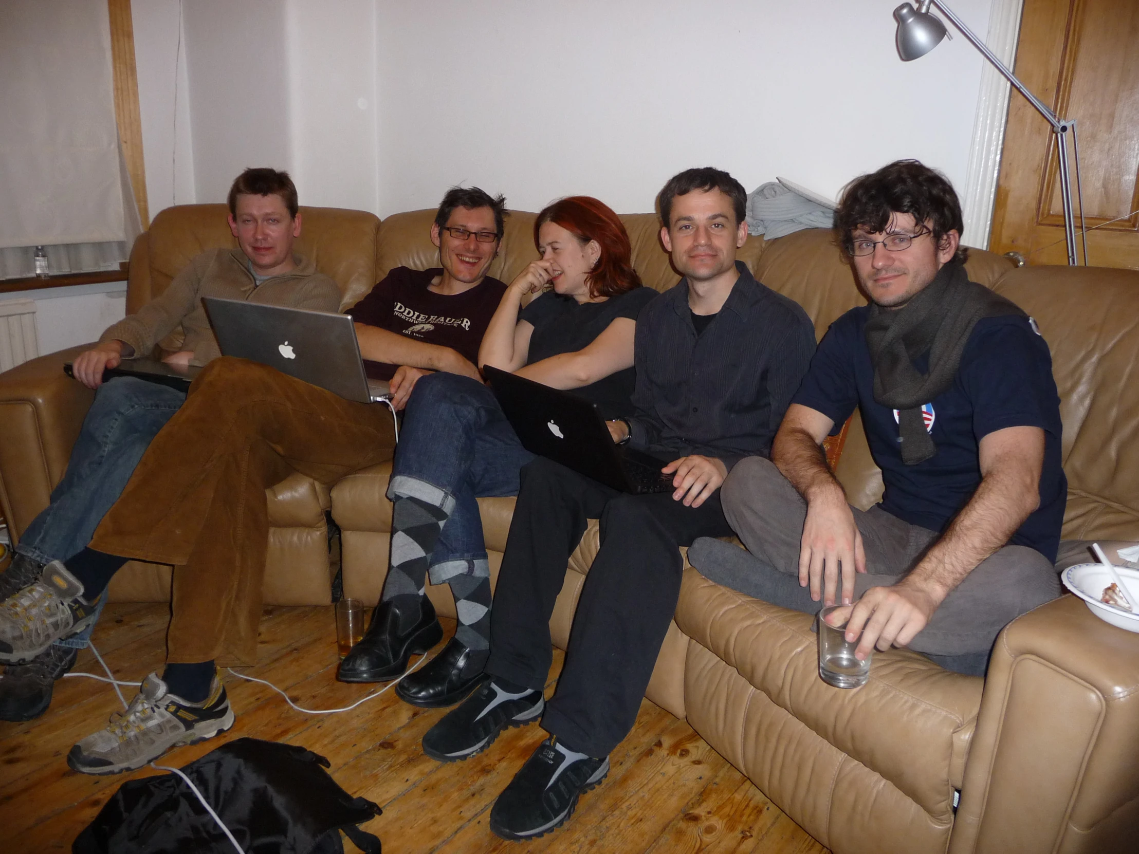 four people sitting on the couch using computers