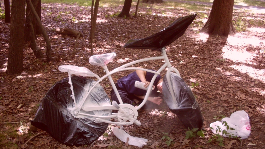 a child with a broken white bicycle in a wooded area