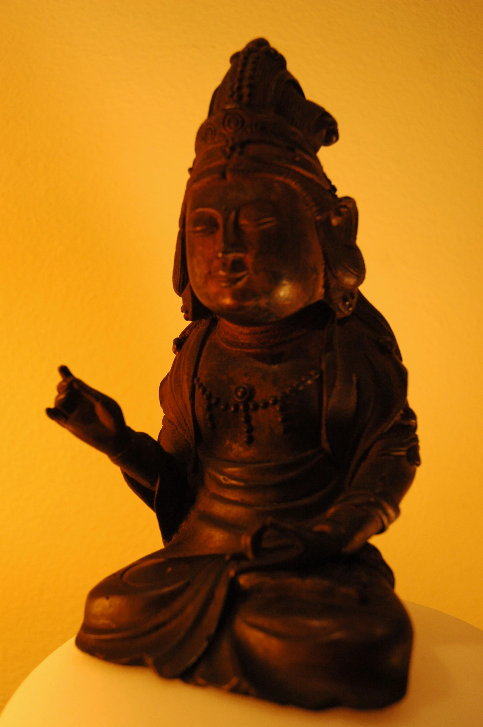 a wooden statue of buddha laying down with one hand on a lamp