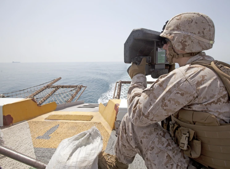 a soldier taking a po with a boat in the background