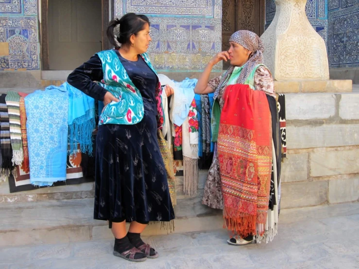 two women in traditional clothing standing in front of an entrance