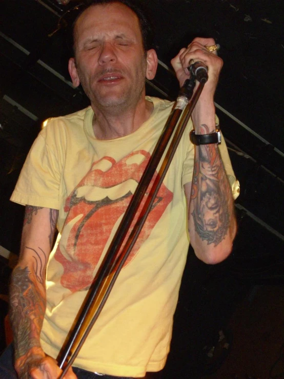 man with tattoos singing and holding a bass