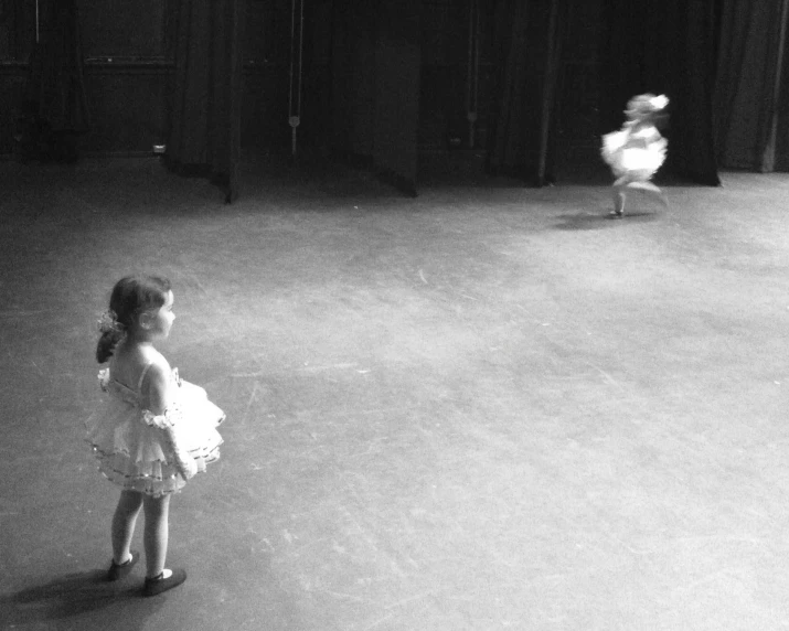 a little girl with white dress on walking near a dancer