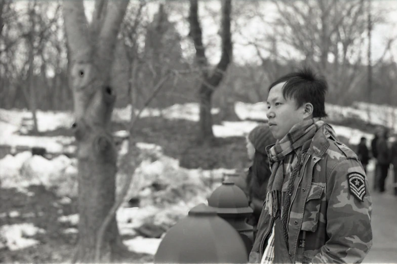 a man wearing an army coat near trees