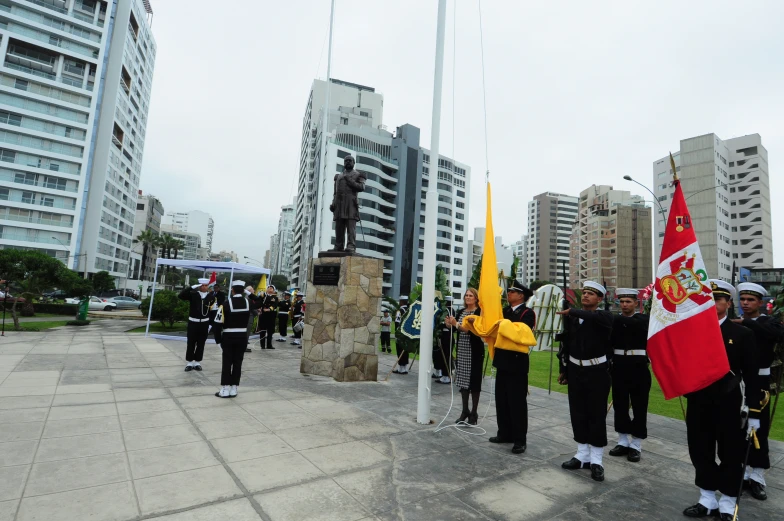 group of men holding flags standing next to a statue