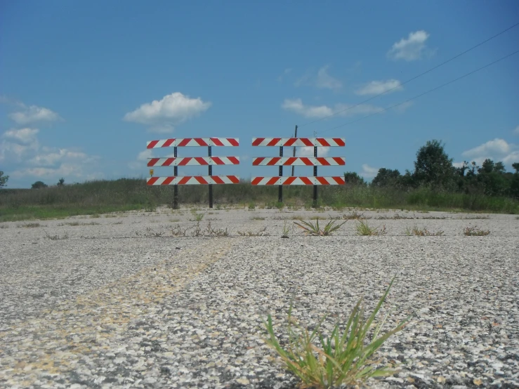 three warning signs sitting in the middle of a gravel field