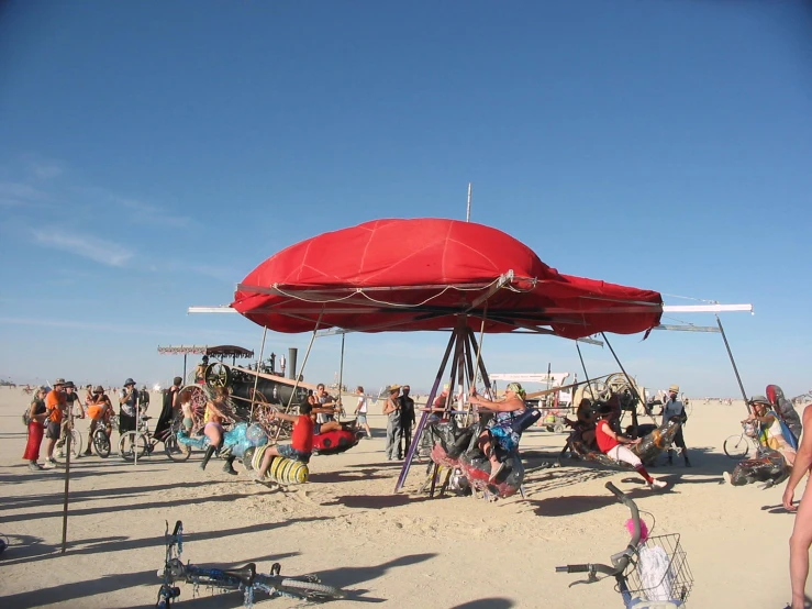 a large group of people sitting and standing around on the beach