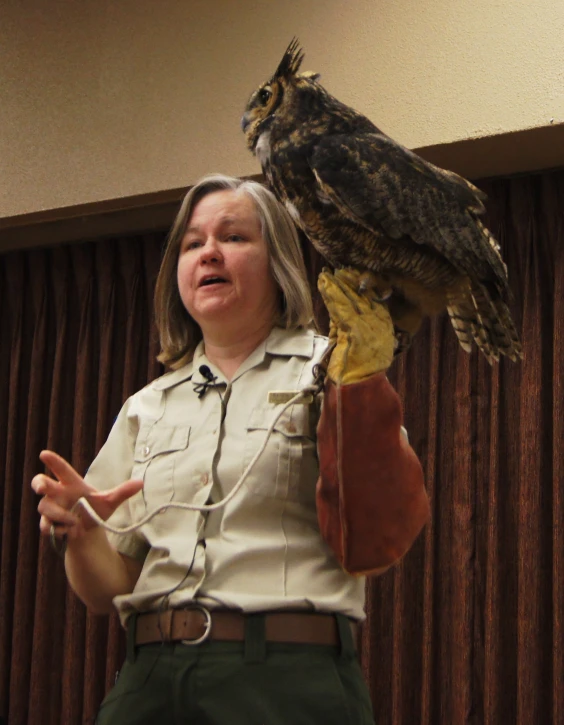 a woman holding an owl on her arm