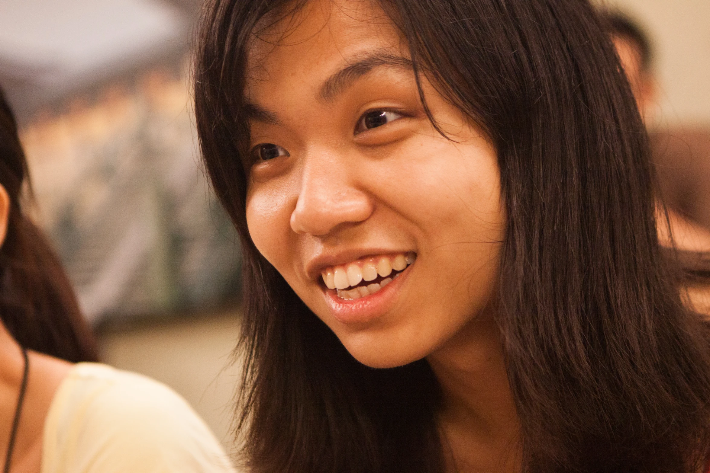 young woman smiling at camera near older person in background