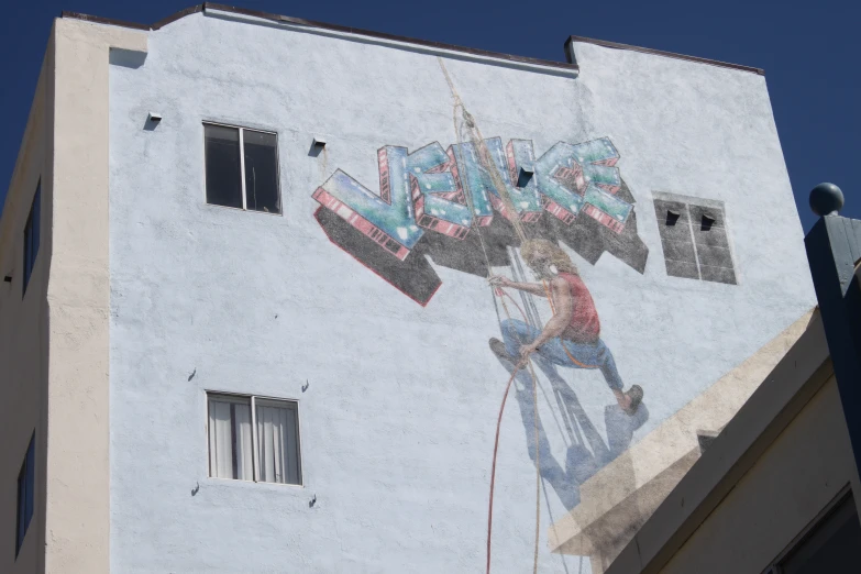 the sky and a large white building have a mural on it