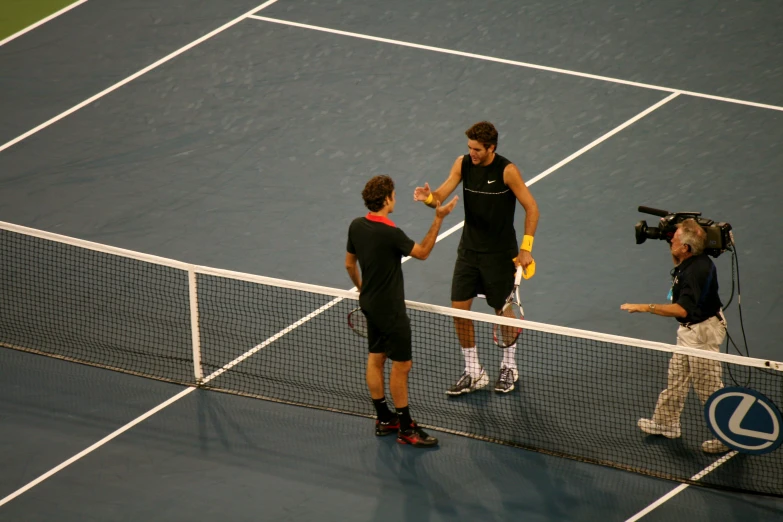 two tennis players shake hands on a court