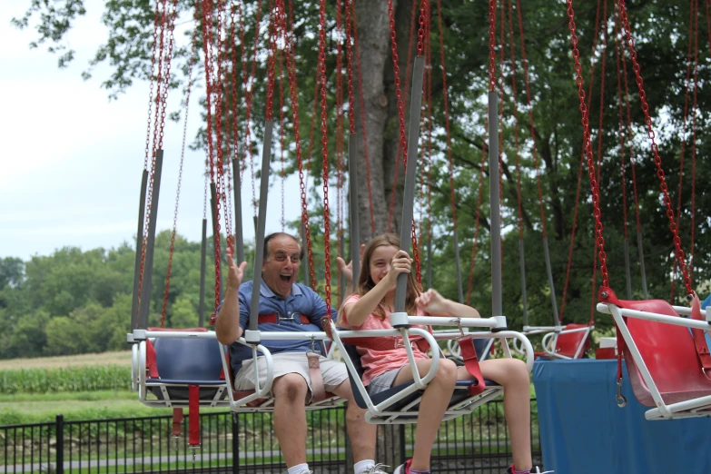 a man and a girl sit in a swing chair