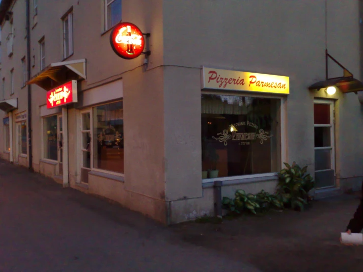 a storefront that is shown at night on the side of a road