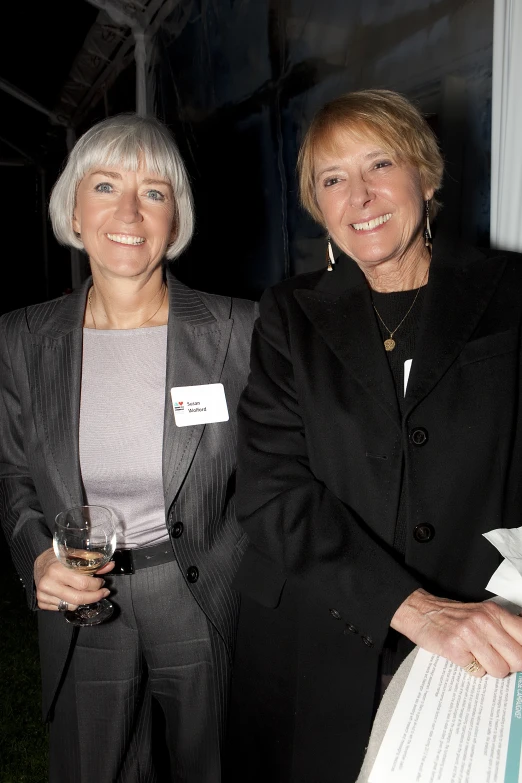 two older ladies stand together holding drinks