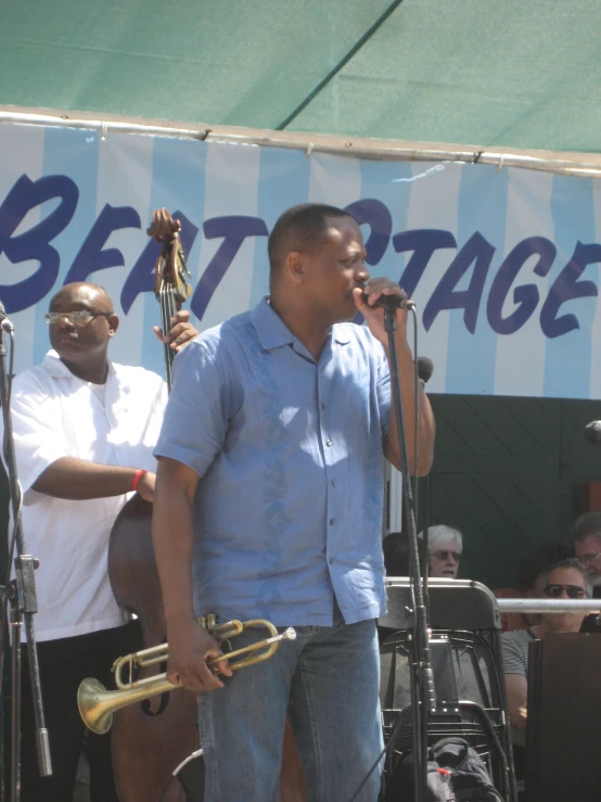 a man standing on stage with a trombone and a microphone