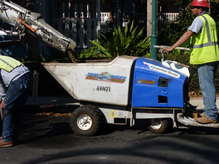 two construction workers with a trash picker, one with a large metal pipe