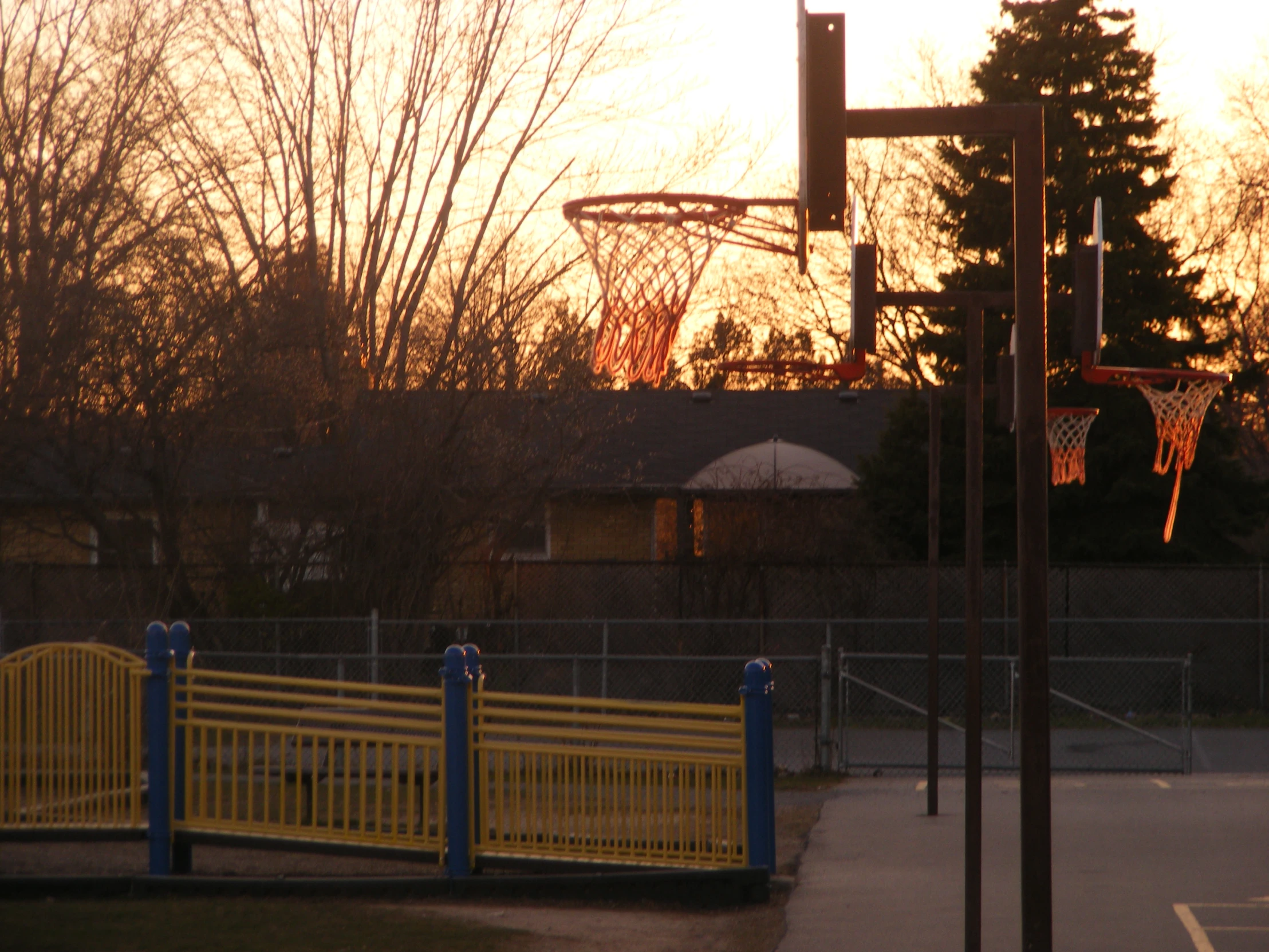 a basketball hoop at the end of a yellow fence