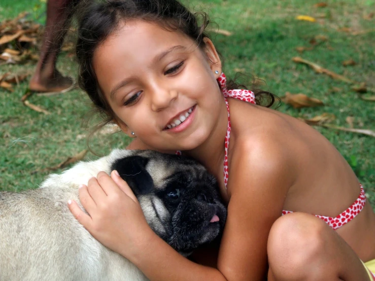 little girl smiling and hugging a black and white dog