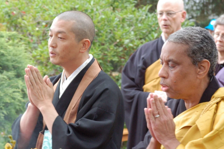 two men in robes are looking at soing while others are clapping