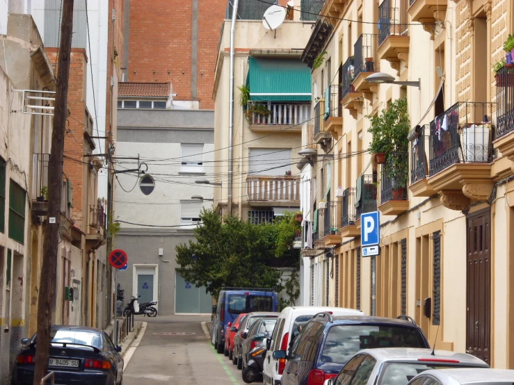 an empty street has many parked cars and apartment buildings