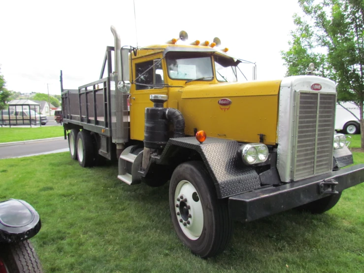 the large truck is yellow in color parked on grass