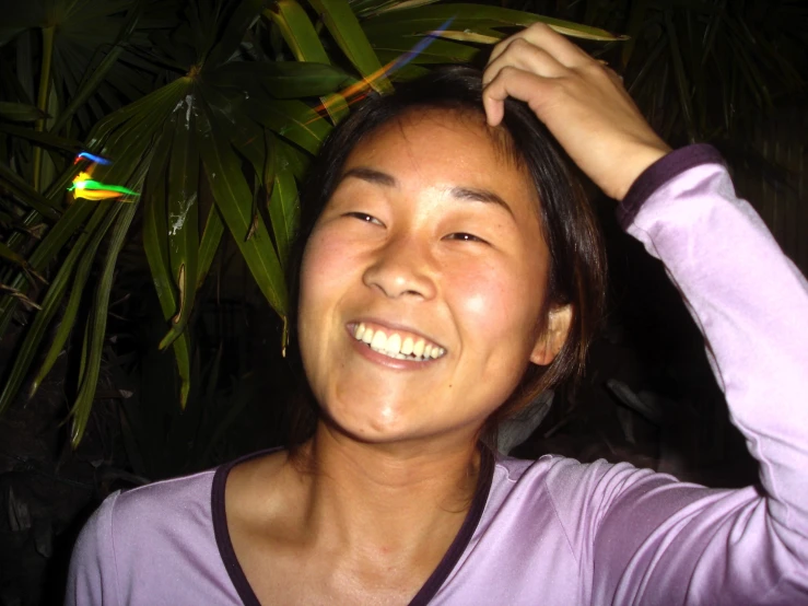 a woman smiling at the camera wearing purple and has her hair pulled back