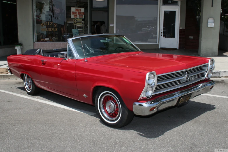 an old red convertible car is parked in a lot