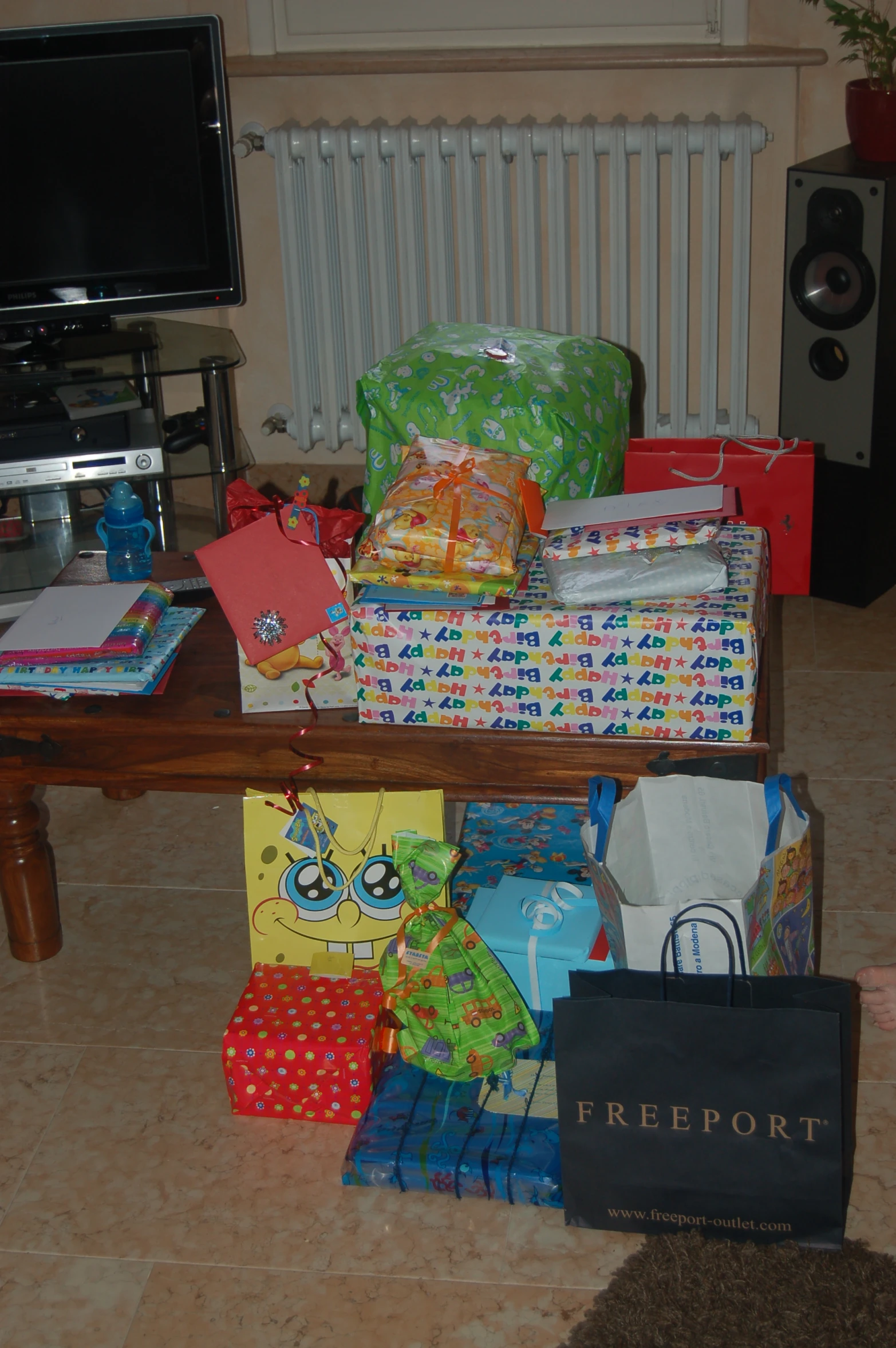 several stacks of wrapped presents sitting on the floor in front of a tv