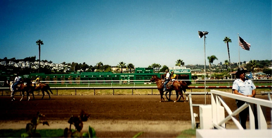 horses are racing on a track with jockeys in the stands