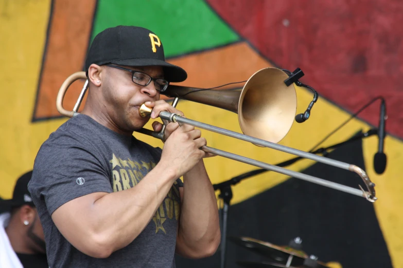 a man in black hat playing on a trombone