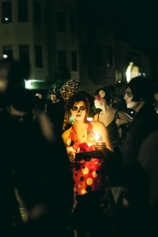 woman with polka dots dress on and hat holding lit candle