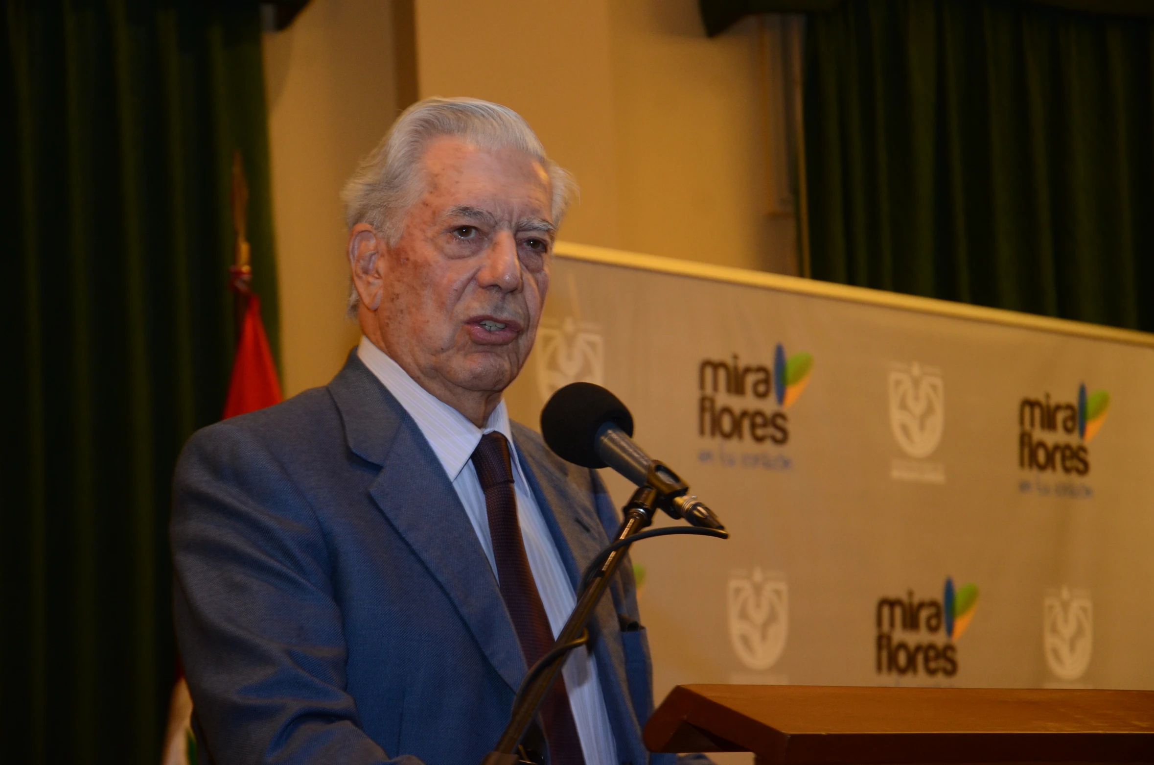 an old man speaking at a podium with microphone