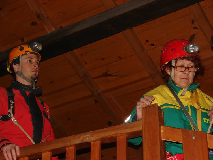 two people wearing hard hats and standing on a balcony