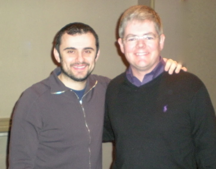 two men standing in front of a brown wall