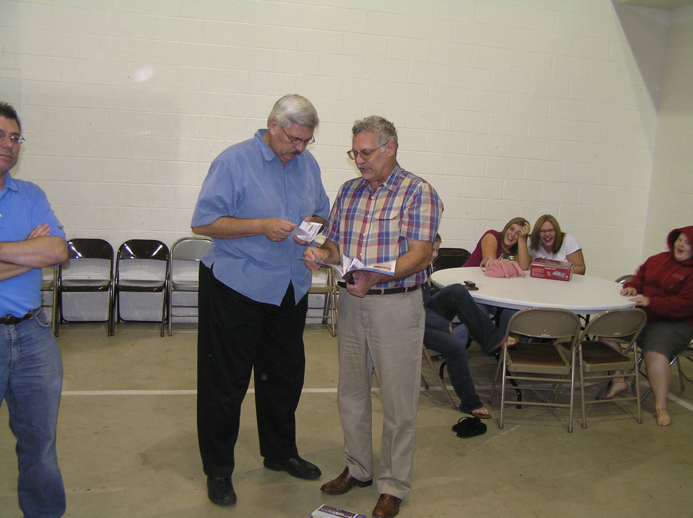 two men standing and talking while others watch