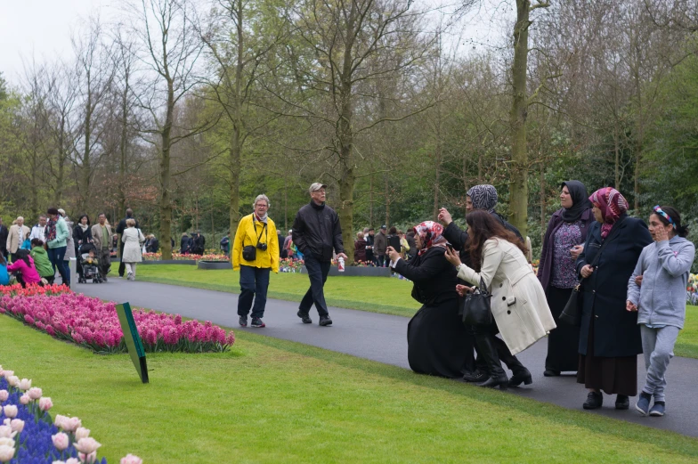 a group of people in the park with many flowers