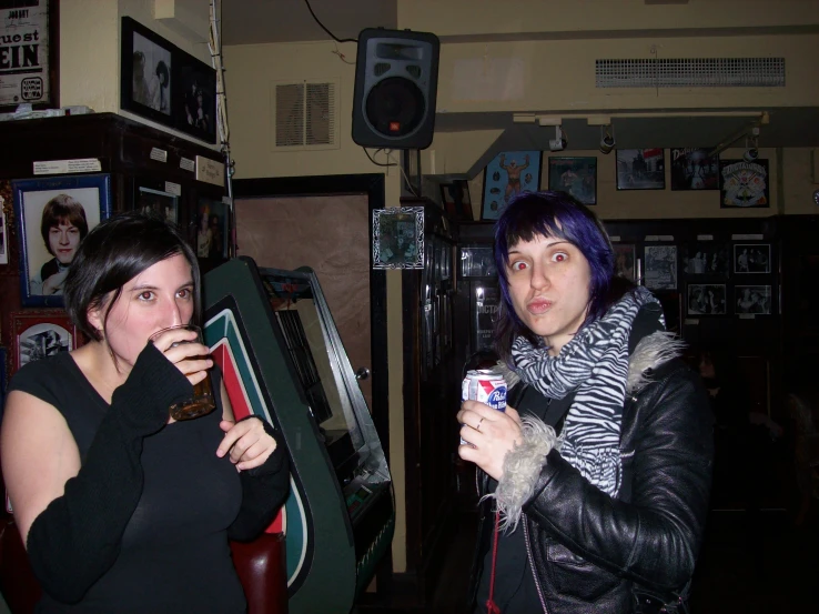 two young women in black outfits, one of them holding a beer