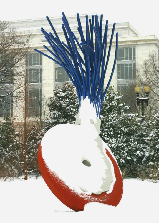 a very colorful sculpture in the snow with trees in the background