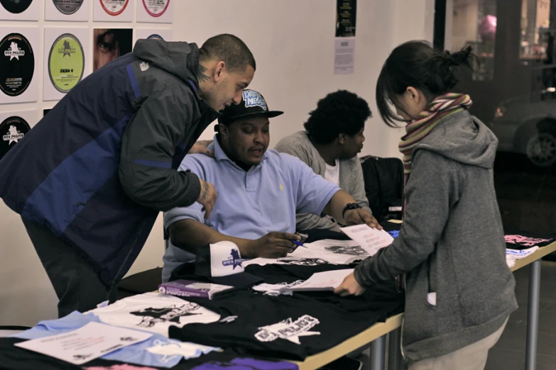 man helping another person choose a pair of t - shirts