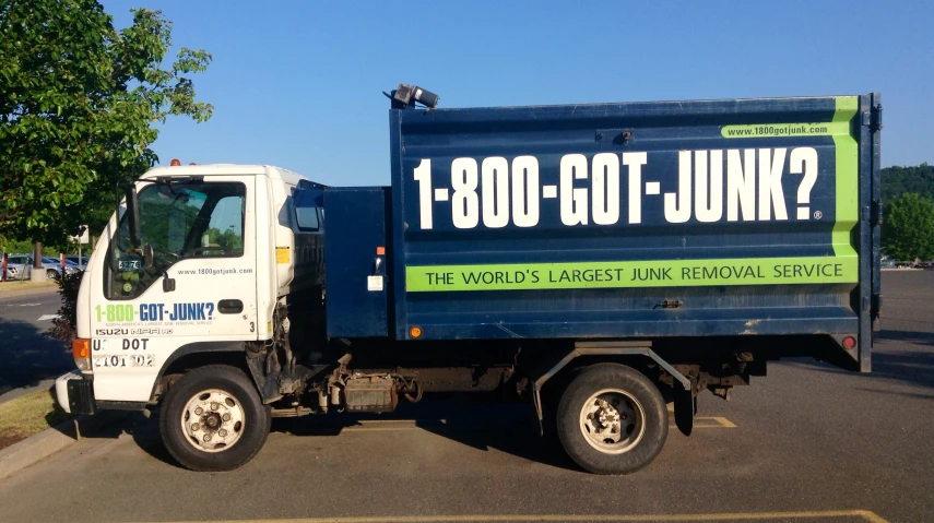 the blue garbage truck is parked on the road