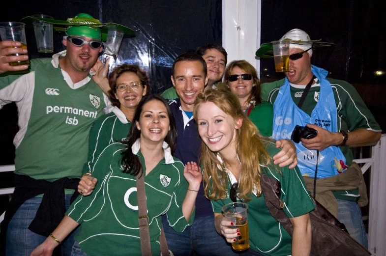 a bunch of people wearing green shirts and holding beer