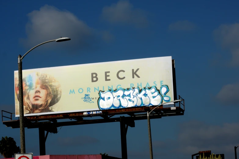 a billboard for beck on a street near a traffic light