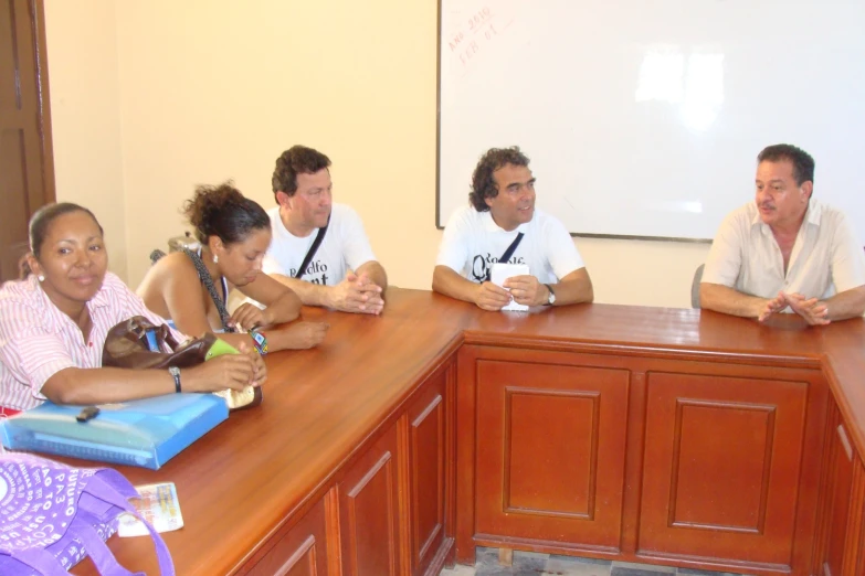 five people sitting in a meeting room with one person holding a laptop