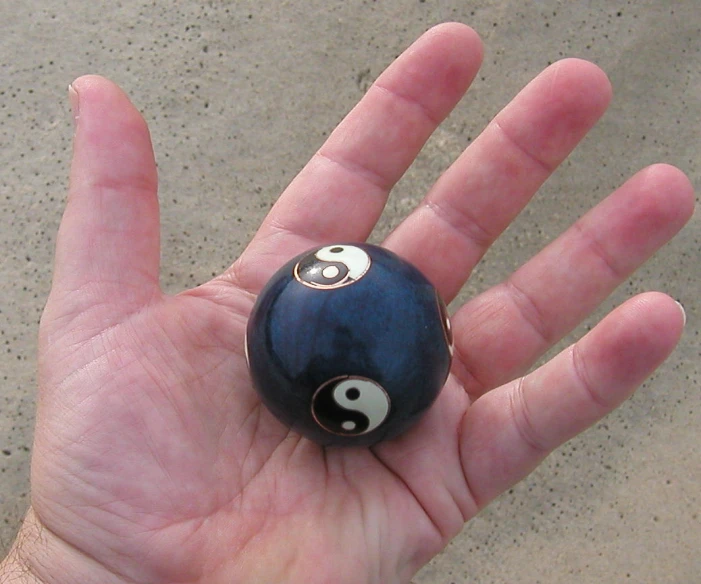 a hand holds a black and white ball with a ying - o on it